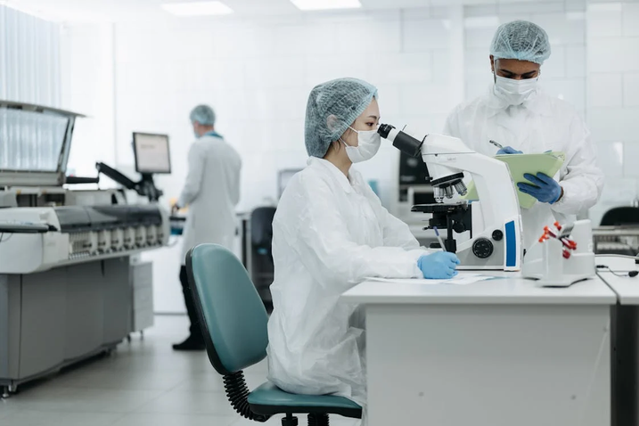Two medical people at a laboratory looking through a microscope